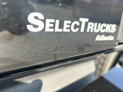 SelectTrucks Atlanta logo on truck body showing part of a Freightliner Cascadia label.