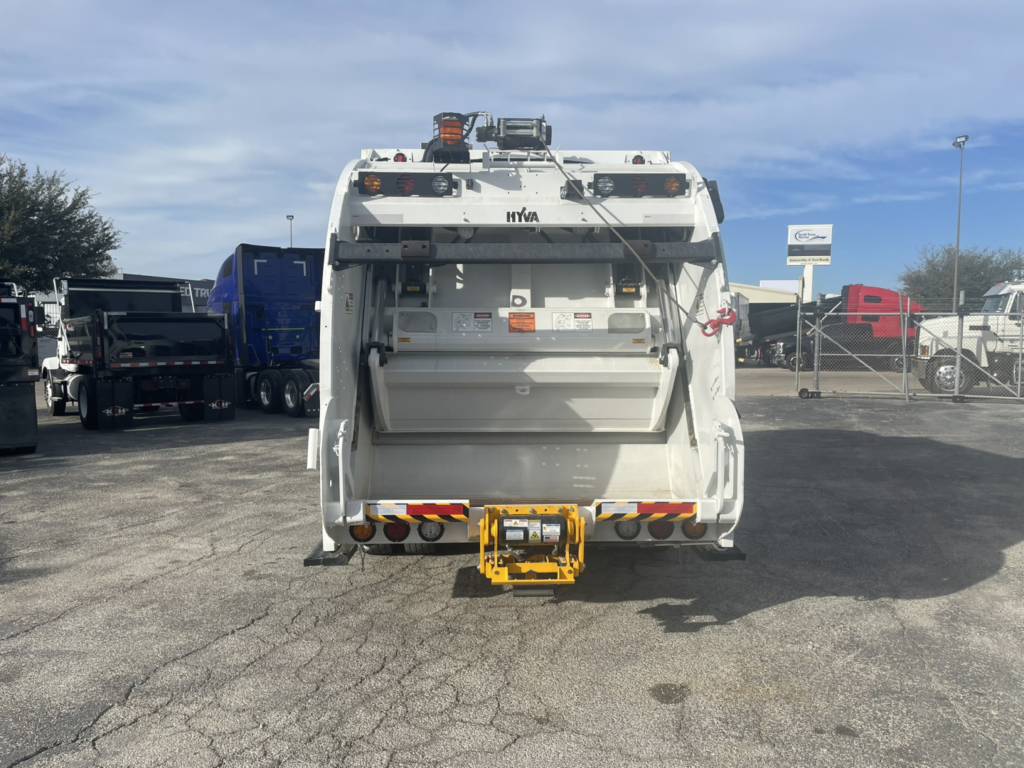 Rear view of a 2026 Mack MD7 refuse truck showing the rear hopper and yellow hitch attachment.