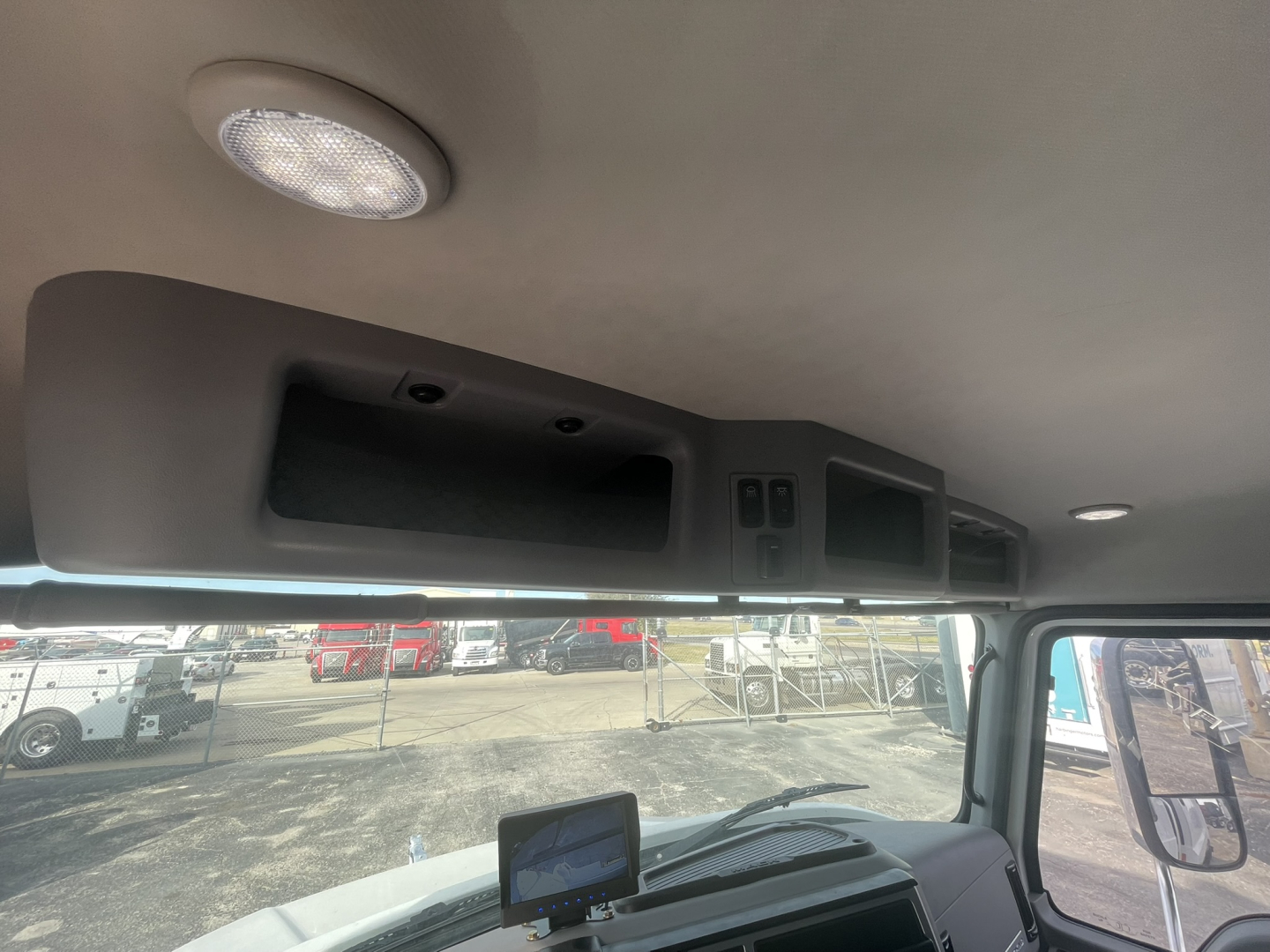 Mack MD7 cab interior overhead storage and dash area visible from windshield, with overhead compartments and small display screen.