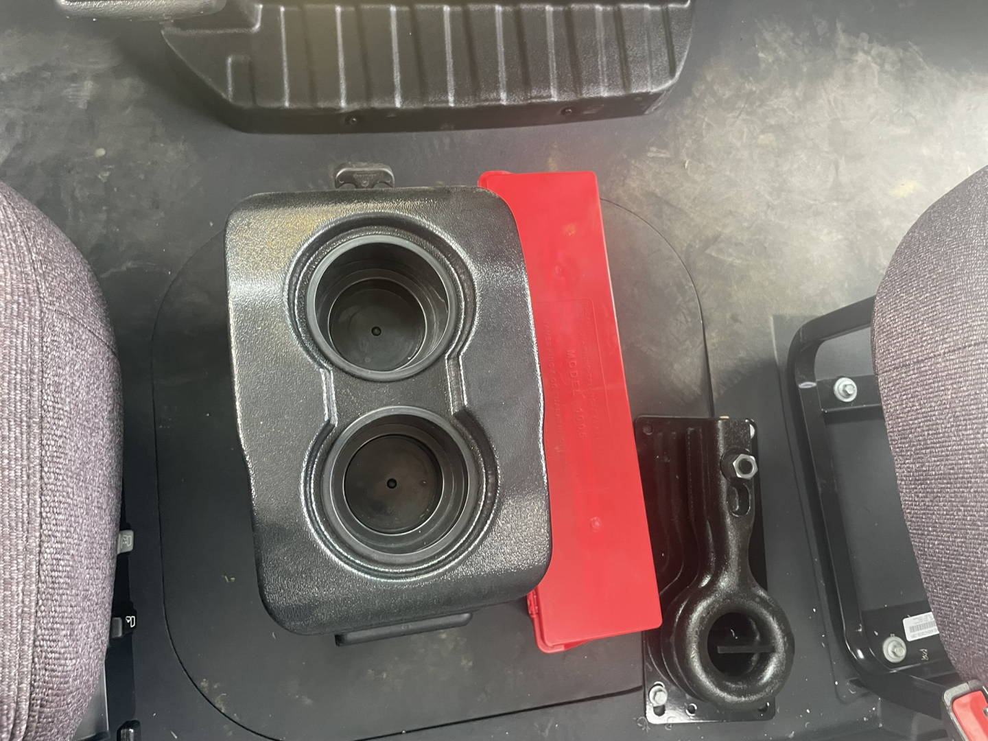 Cab interior showing two cup holders and a red rectangular panel between seats in a Mack MD7 truck.