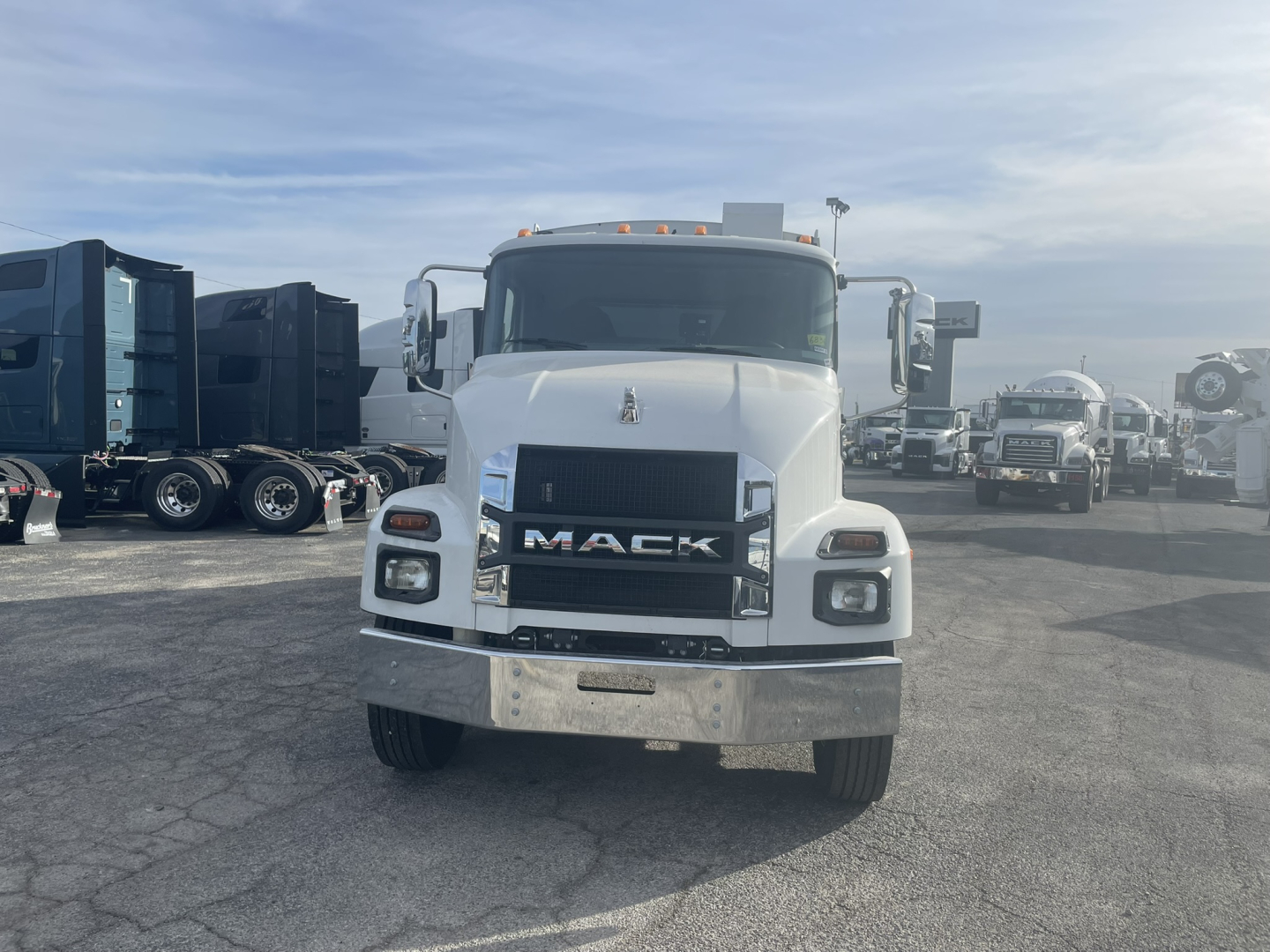 Front view of a white 2026 Mack MD7 refuse rear load truck showing Mack grille and bumper in a dealership lot.