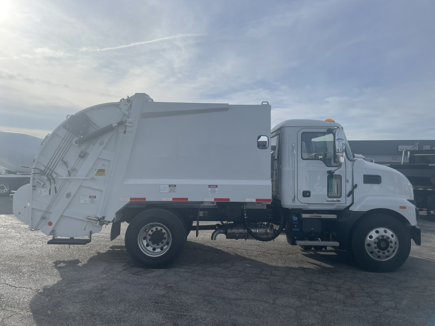 Mack MD7 refuse truck in side profile showing dump bed and cab with VIN 1M2MDBAA1TS077666 on listing.