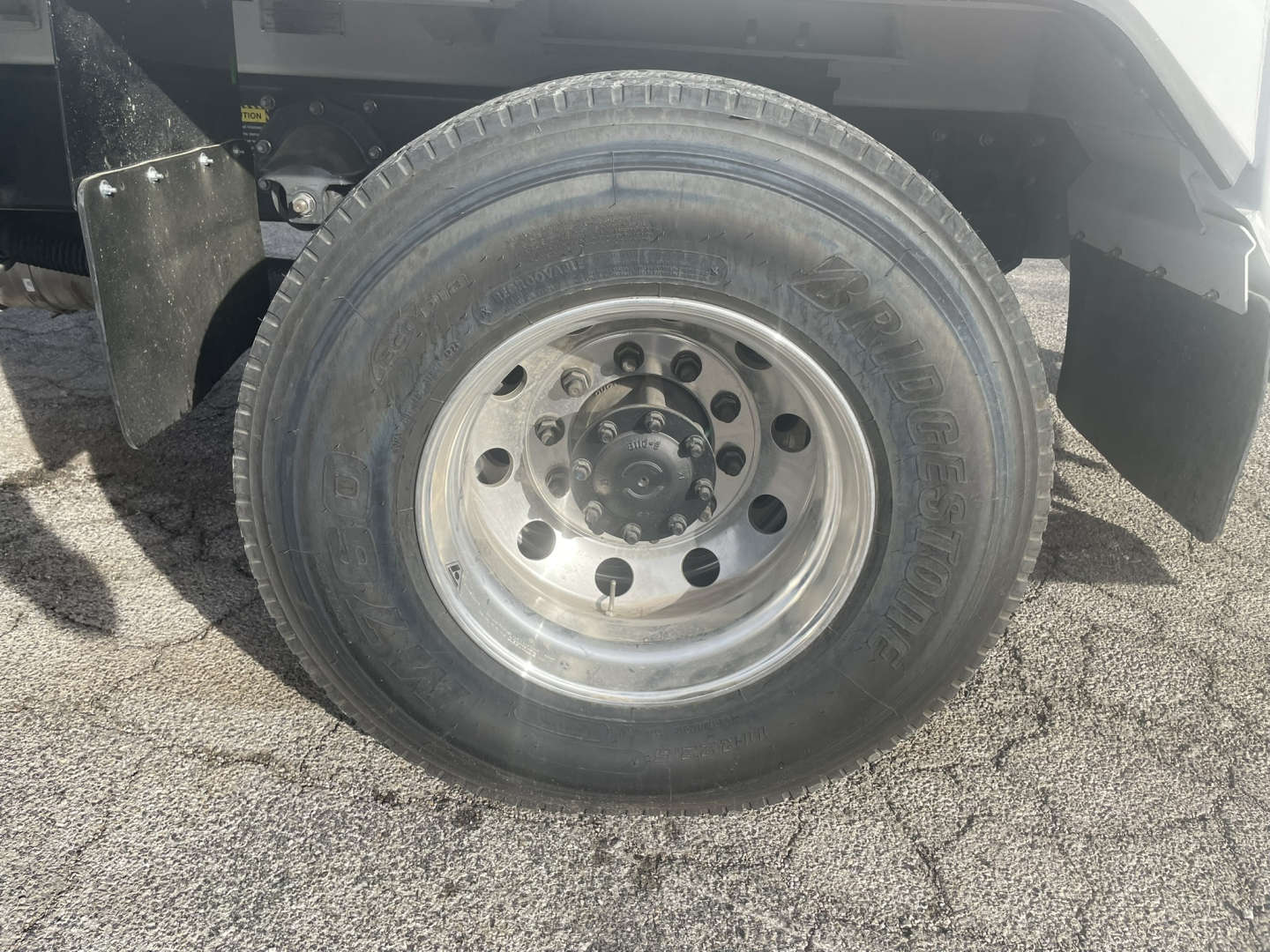 Truck wheel close-up showing steel rim and tire sidewall on Mack MD7 refuse truck.