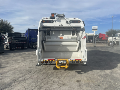 Rear view of a 2026 Mack MD7 refuse truck showing the rear hopper and yellow hitch attachment.