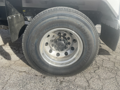 Truck wheel close-up showing steel rim and tire sidewall on Mack MD7 refuse truck.