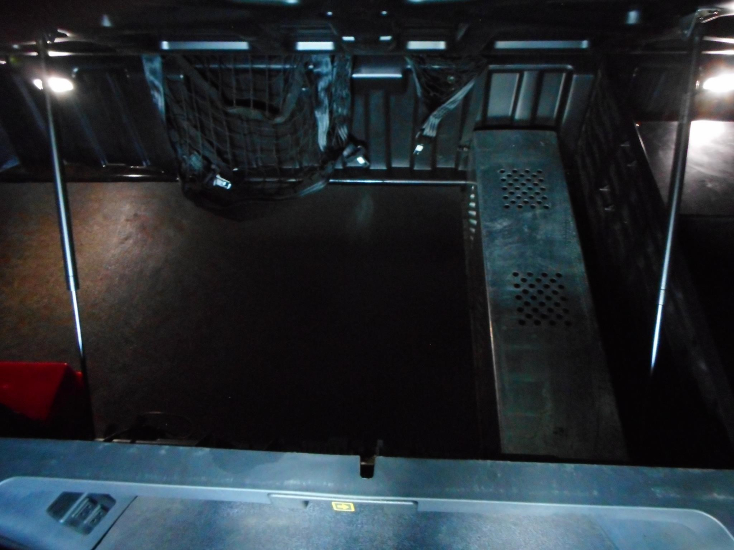 Truck interior cargo area of a 2024 Freightliner Cascadia 126 showing a storage space with a net and perforated metal section.