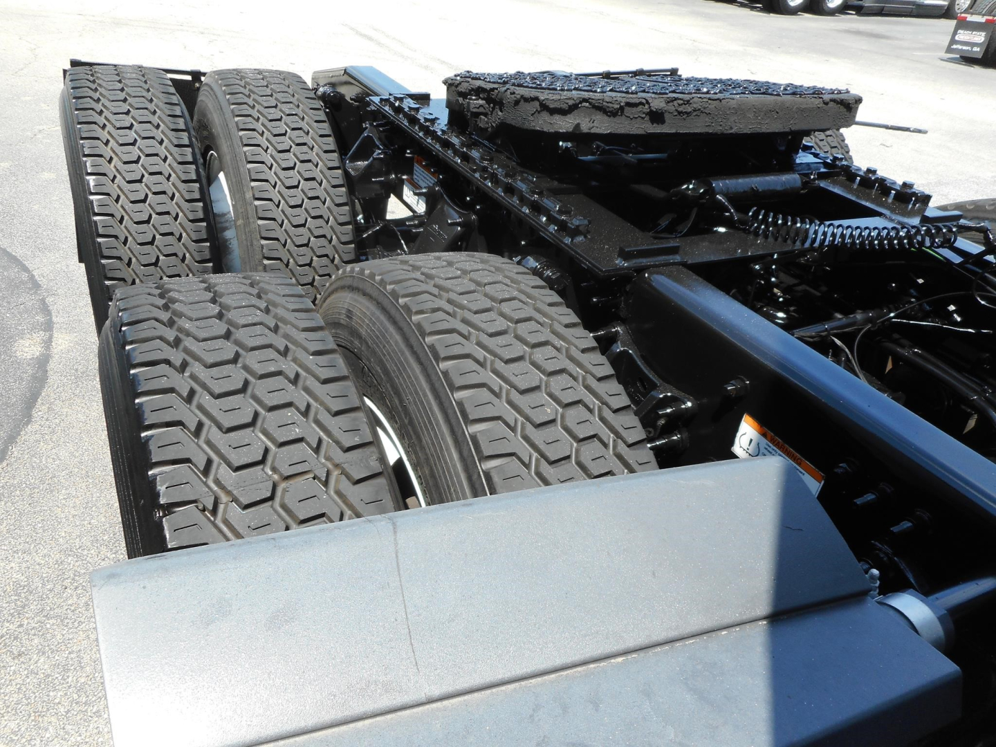 Diesel truck chassis with dual rear axles and heavy-duty tires visible in a Freightliner Cascadia cabless frame.
