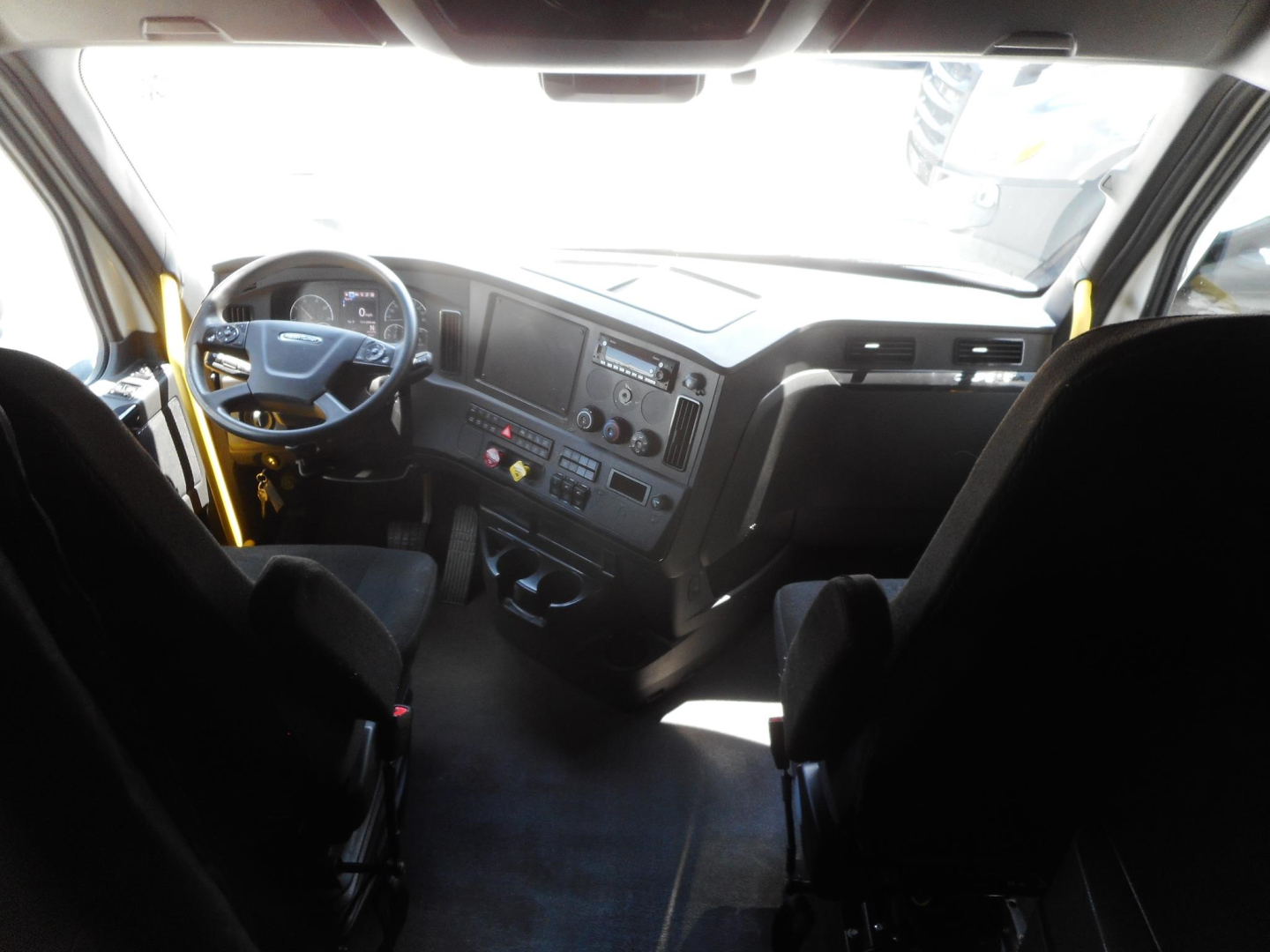 Freightliner Cascadia truck interior dash and steering wheel view from driver seat showing dashboard controls and seating.