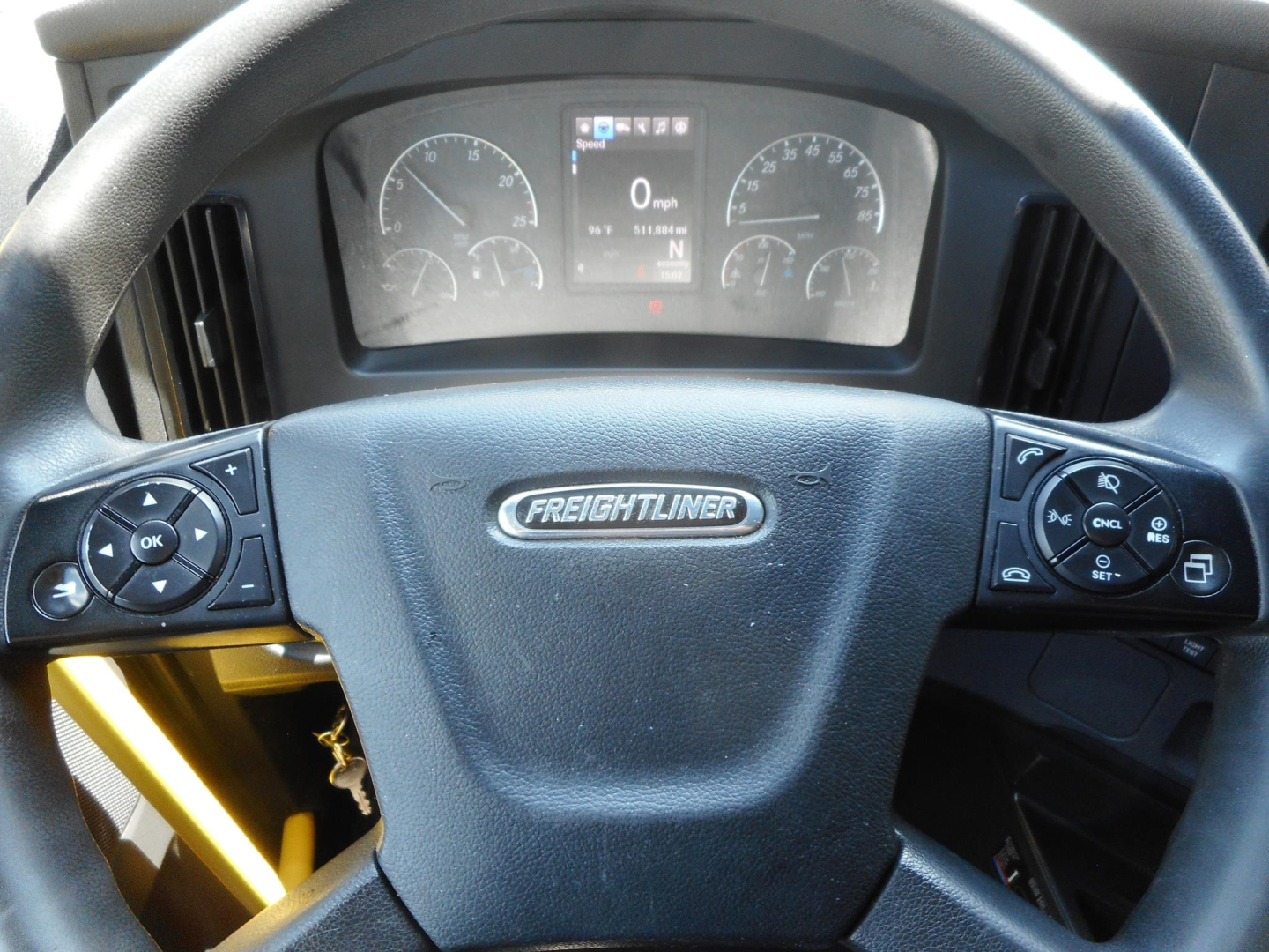 Steering wheel of Freightliner Cascadia truck with digital gauge cluster in background.