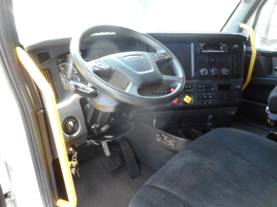 Truck cab interior showing steering wheel, instrument cluster, and dashboard of a Freightliner Cascadia 126 day cab with driver seat and pedals visible.