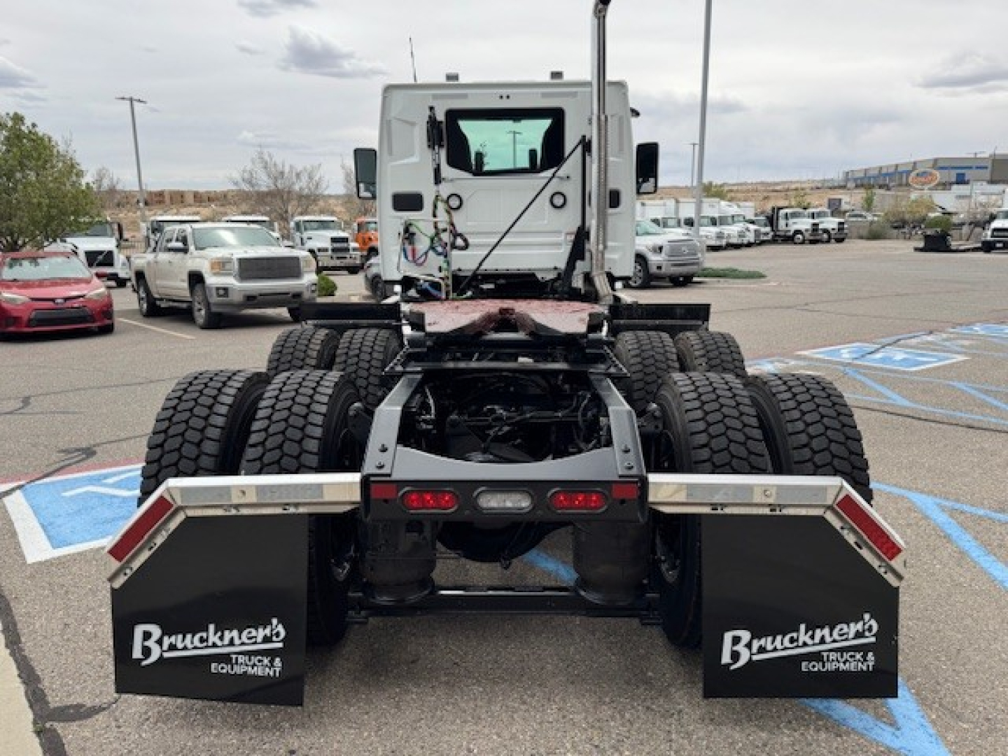 Rear view of a new 2027 Mack AN64T daycab tractor showing dual rear axles, mud flaps with Bruckner’s Truck Equipment logos, and cargo frame.