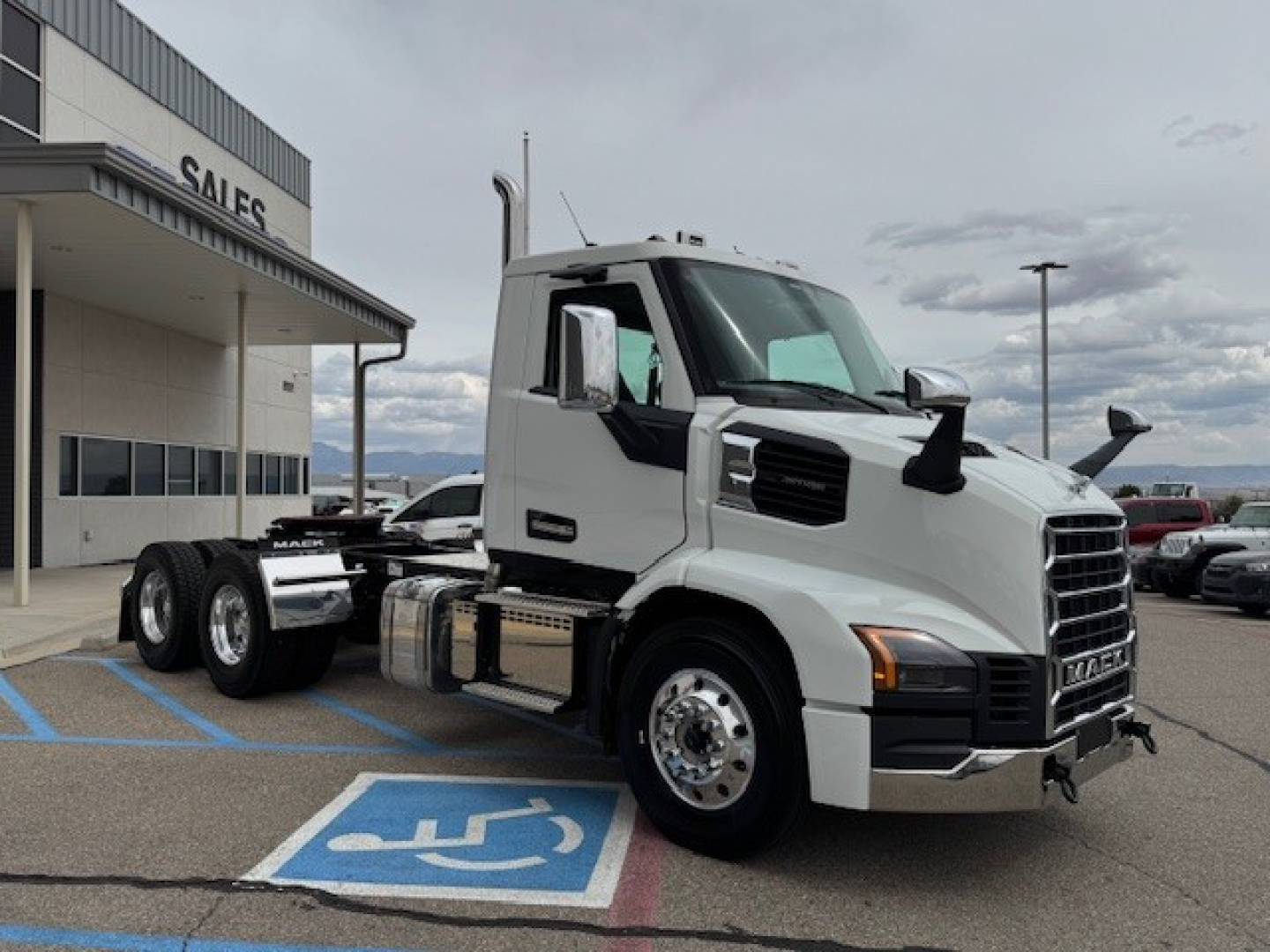 White Mack AN64T conventional daycab truck front-side view showing cab, dual rear axles, chrome fuel tanks, and large side mirrors.