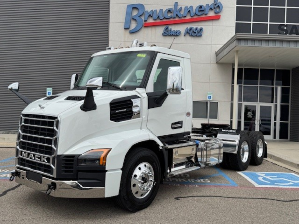 Mack AN64T conventional daycab truck in front of dealership with Brunkner's sign and handicap parking space visible.