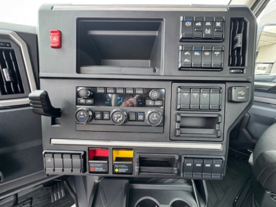Dashboard panel of a 2027 Mack AN64T showing climate controls, switches, and storage compartments.