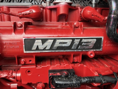 Engine bay of a red Mack MP8/AN64T showing engine badge and wiring harness with labels