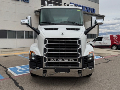 Front view of a white Mack AN64T truck in showroom lot showing grille, headlights, and bumper with 'MACK' emblem.