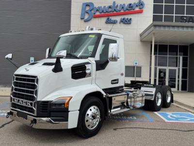 Mack AN64T conventional daycab truck in front of dealership with Brunkner's sign and handicap parking space visible.