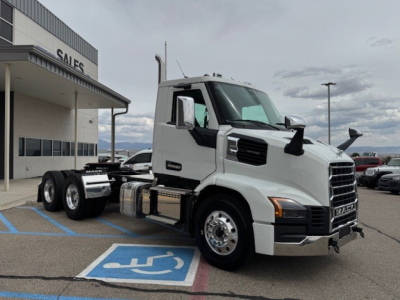 White Mack AN64T conventional daycab truck front-side view showing cab, dual rear axles, chrome fuel tanks, and large side mirrors.