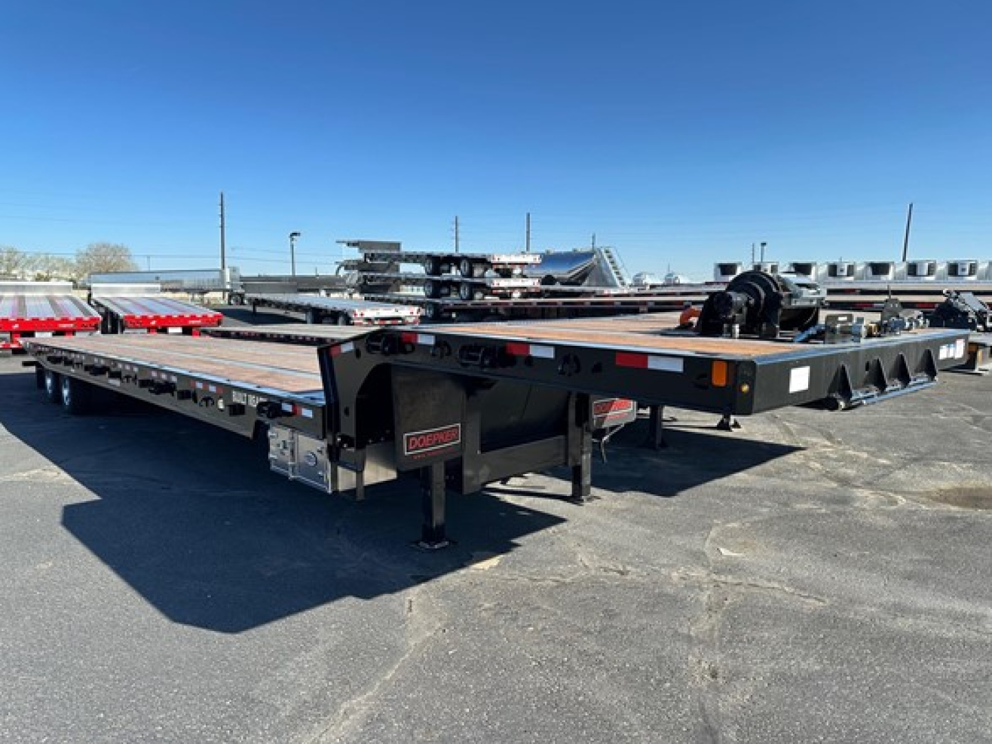Doepker 40 ton slide axle trailer with 20K winch and air ride system, black steel frame, long lowbed sections, front legs and winch housing visible.
