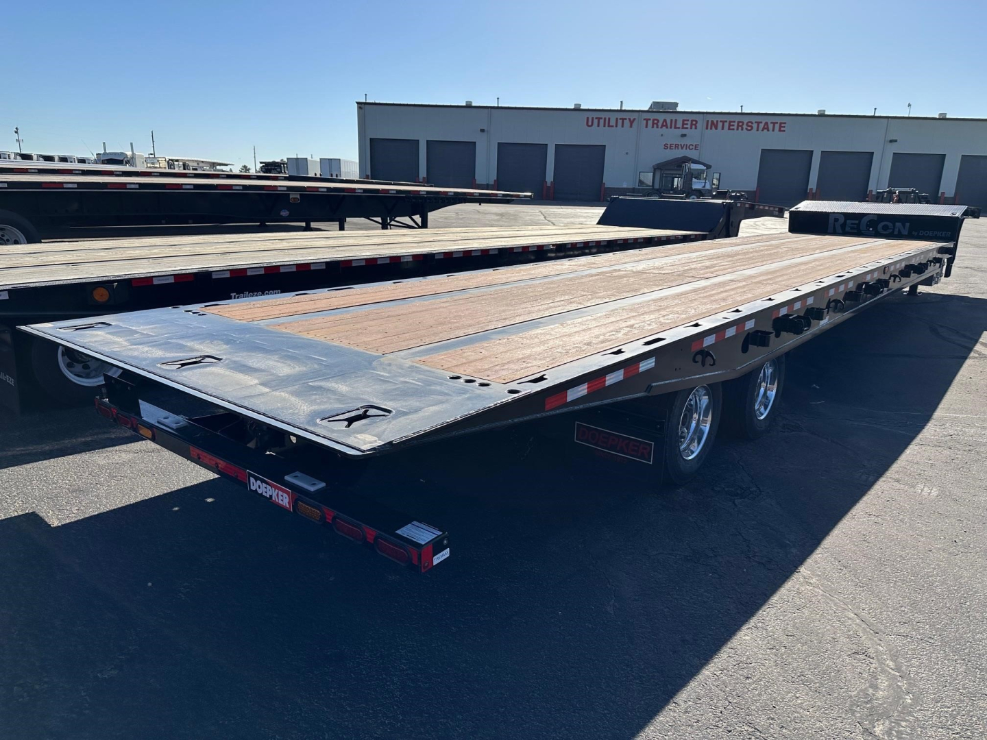 Doepker slide axle trailer with wood deck and dual axle wheels on a parking lot