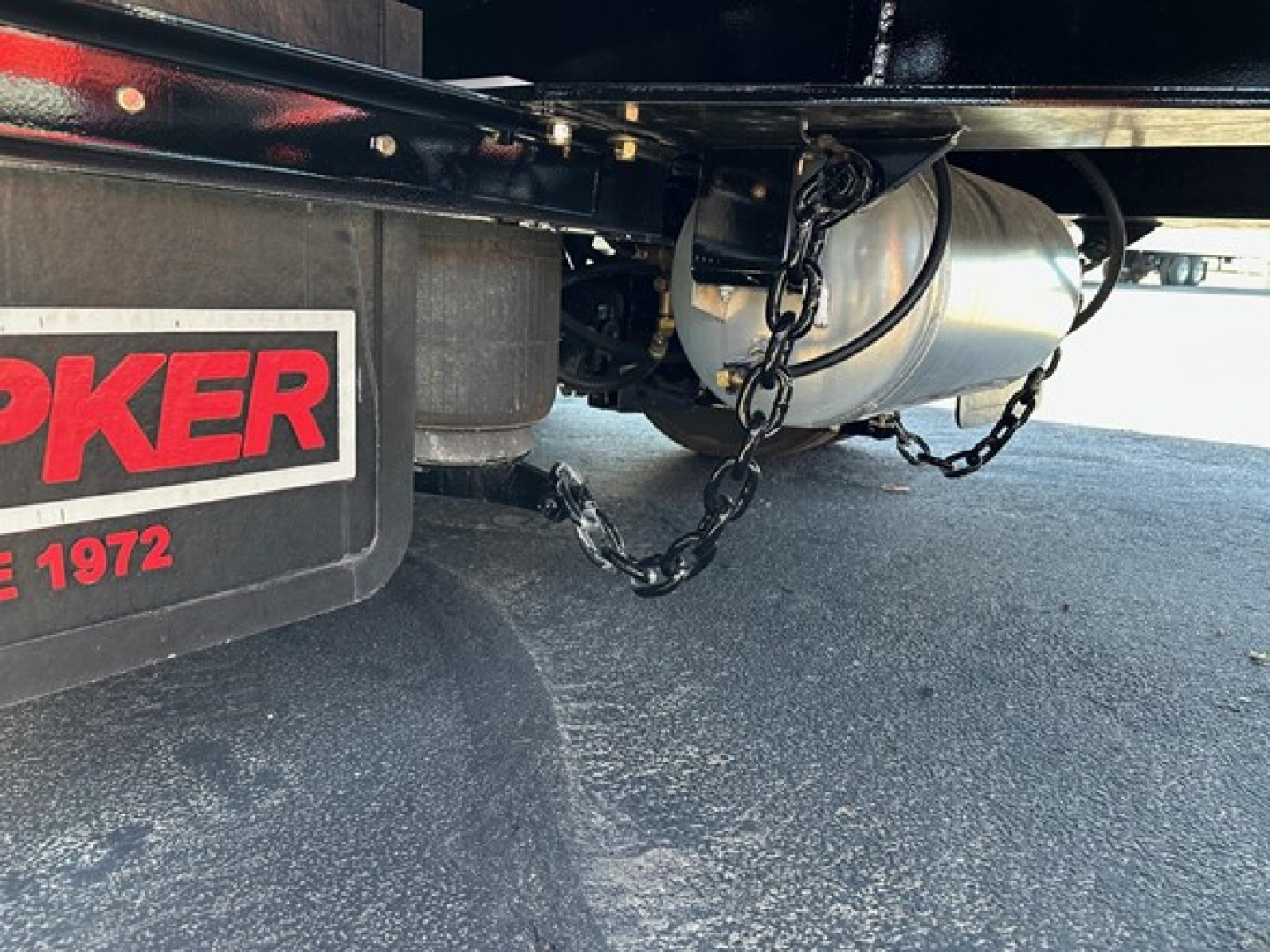 Doepker trailer underside showing air hose/wire chains and winch area with Doepker branding on mudguard