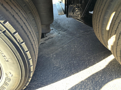 Trailer axle area showing dual wheels and undercarriage components of a new Doepker slide axle trailer.