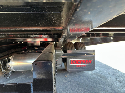 Doepker slide axle trailer undercarriage showing Doepker logo on a black component with red lettering.