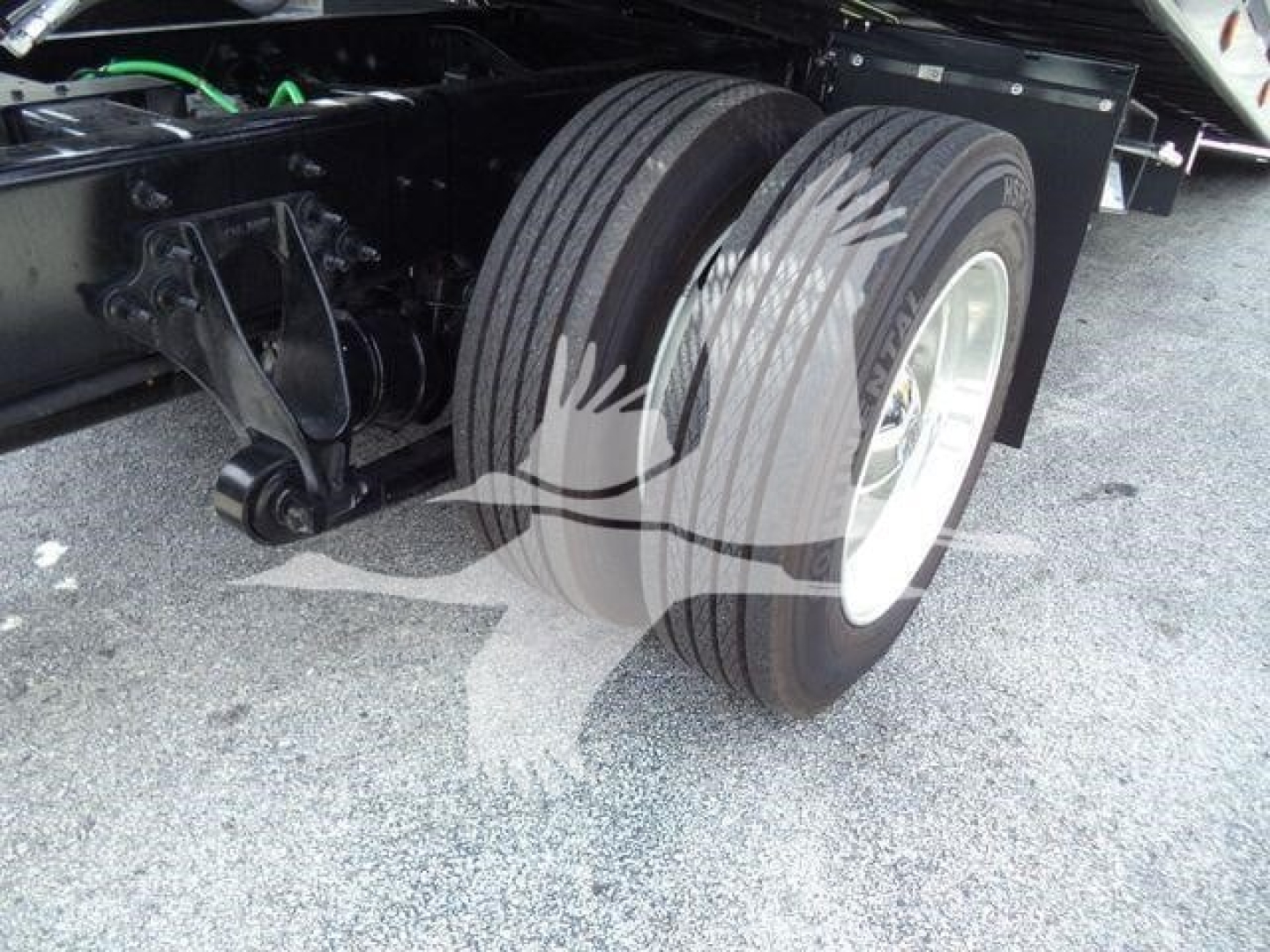Dual rear truck tires and suspension underside view of a 2027 International MV rollback truck showing twin wheels and axle components.
