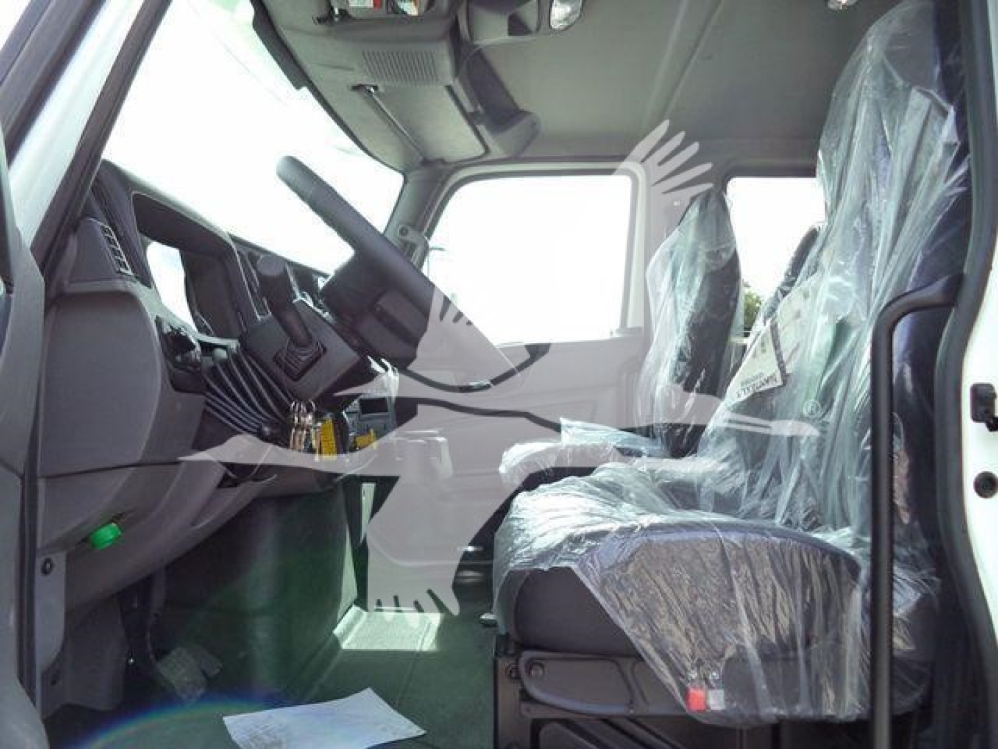Cab interior of new 2027 International MV rollback truck showing steering wheel, dashboard, and plastic-covered seats.