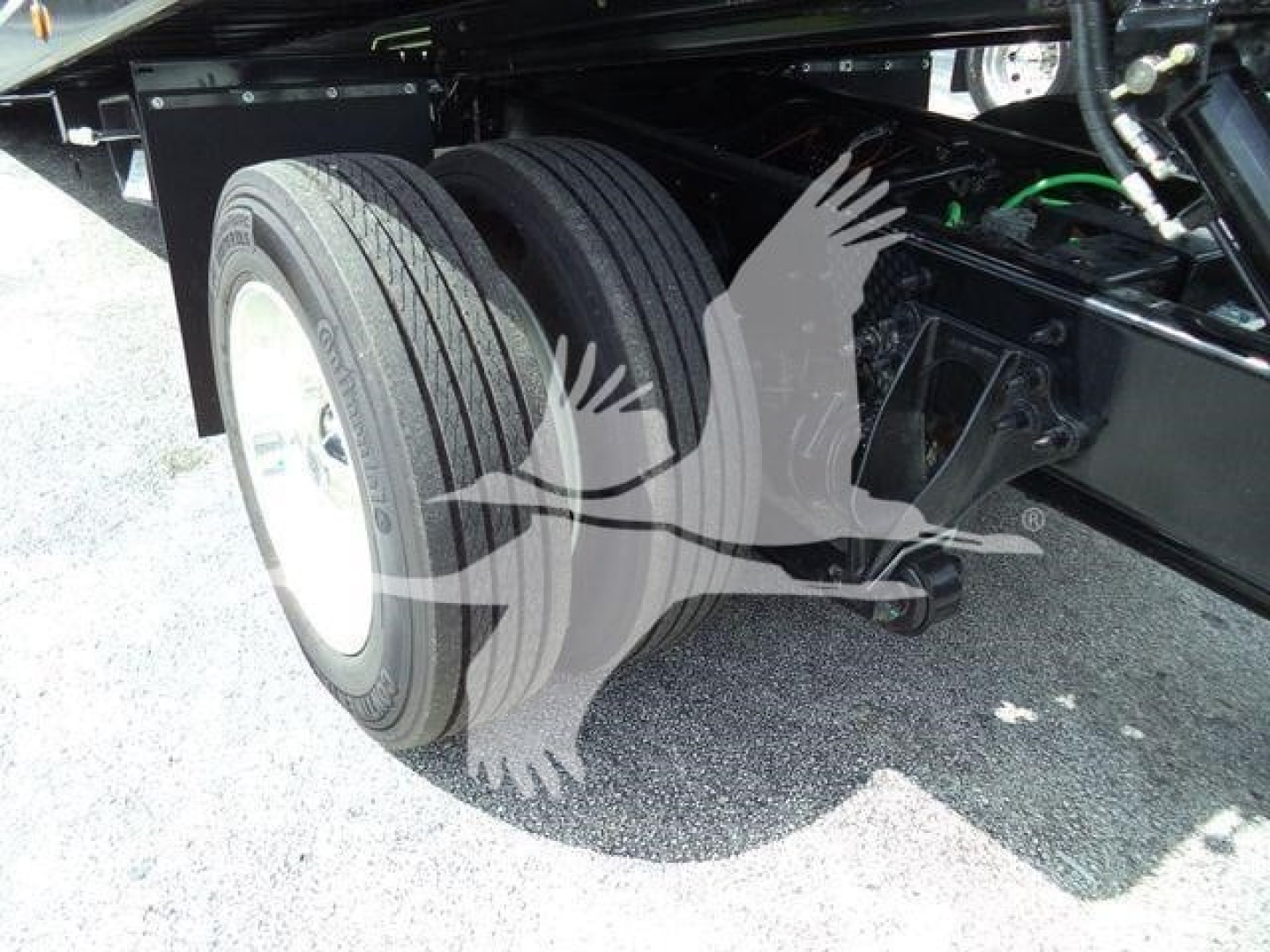 Truck rear dual wheels and suspension showing tires and undercarriage components.