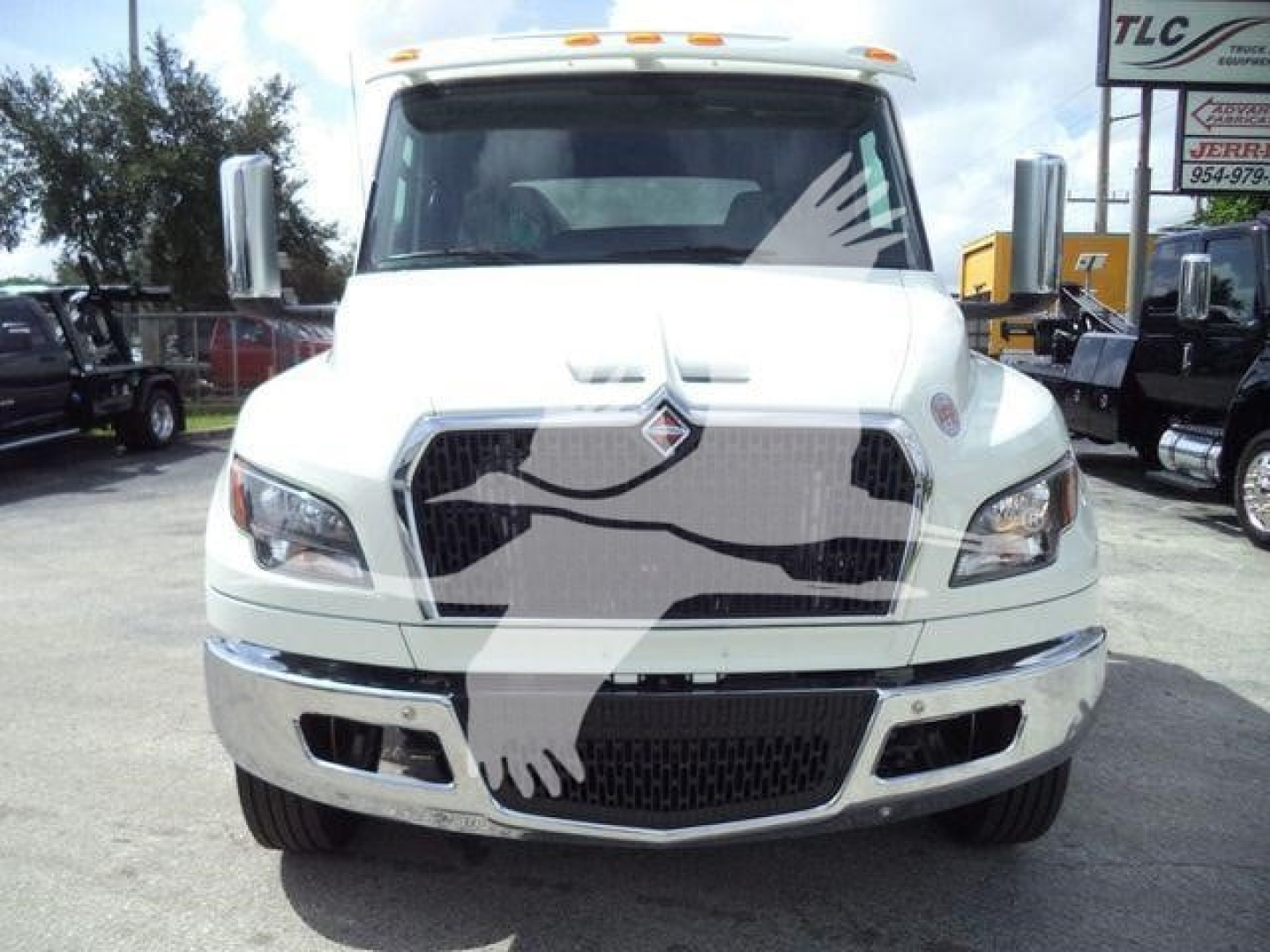 Front view of a white 2027 International MV rollback truck with chrome grille, large bumper, and dual side mirrors.