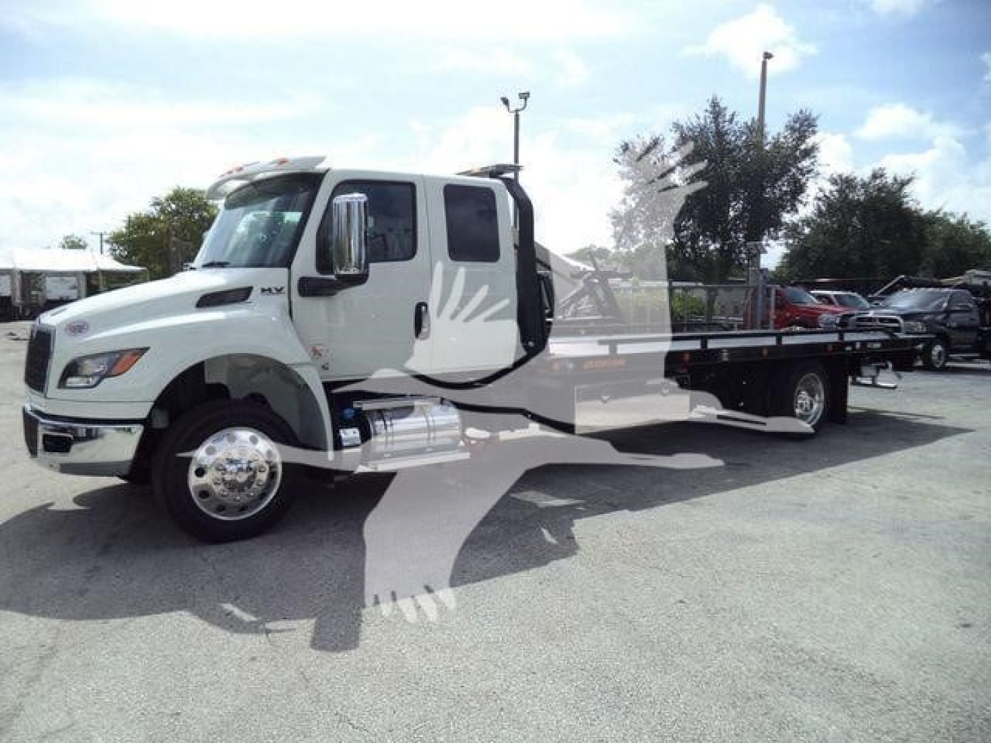 White International MV rollback tow truck from a side view showing flatbed and cab with chrome mirrors and dual rear wheels.