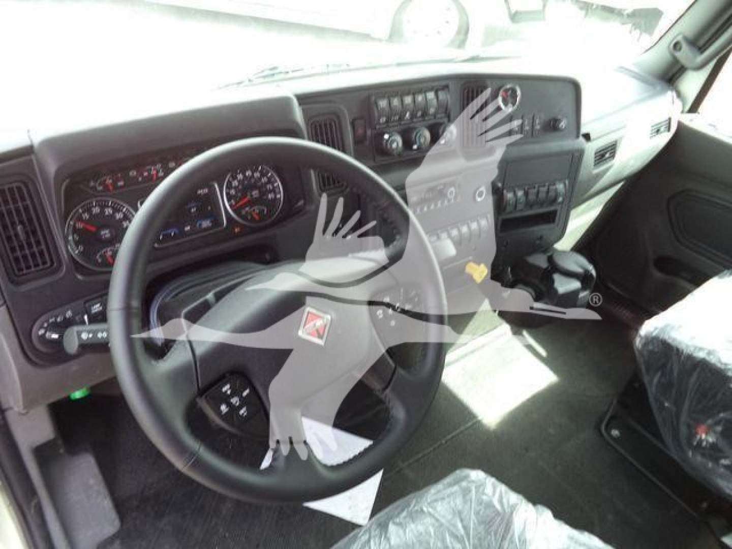 Truck cab interior showing steering wheel and dashboard in a 2027 International MV. Visible gauges, center console, and gear shifter.
