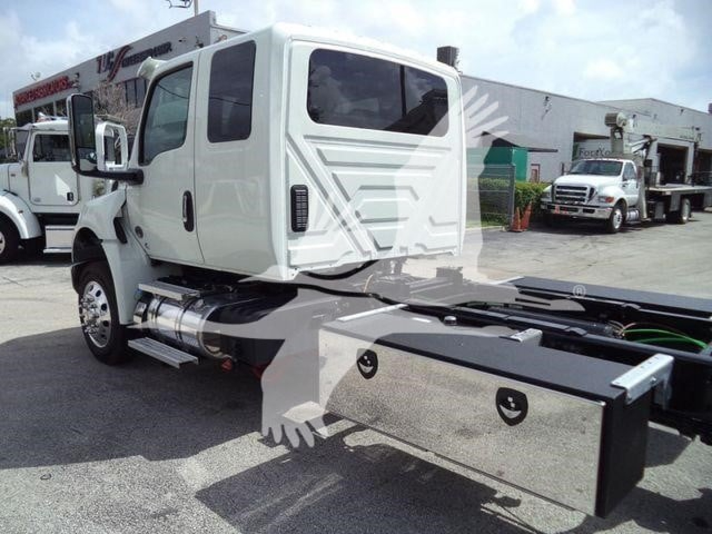 Truck cab side view showing side storage toolbox and fuel tank with chrome fuel caps; white International MV rollback truck.