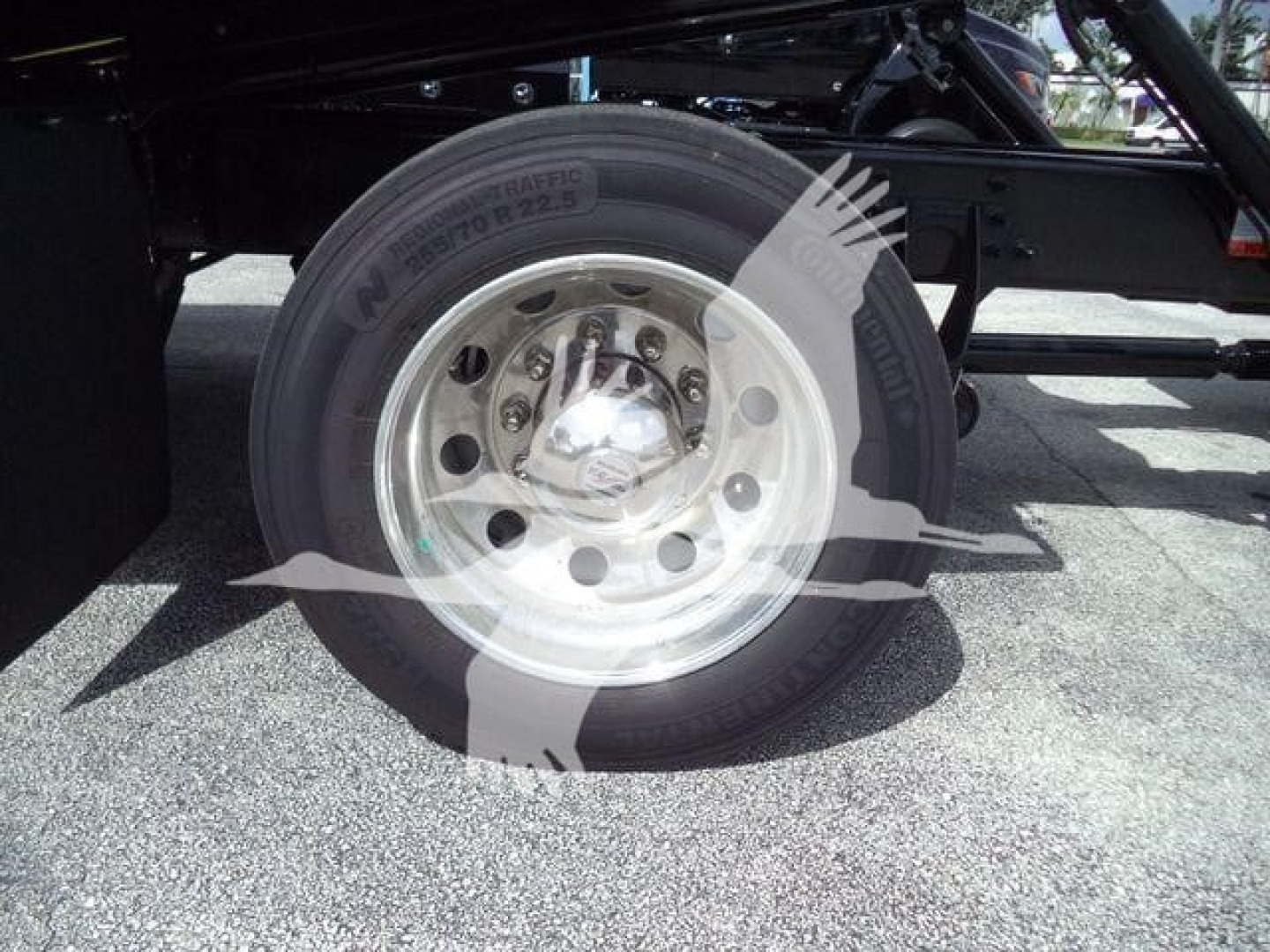 Wheel and tire of a new International MV rollback truck showing N/A tire markings and chrome hub with lug nuts.