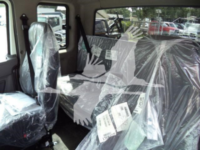 Cab interior of new 2027 International MV rollback truck showing plastic-covered seats and label tags.