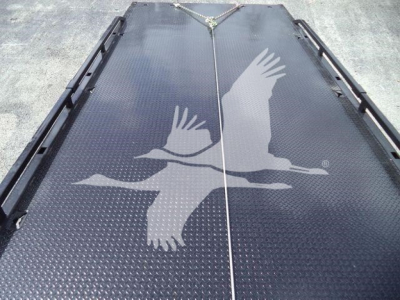 Flatbed or loading deck with two large bird logos (eagles) in a light color; tie-down straps visible at top center; black textured surface.