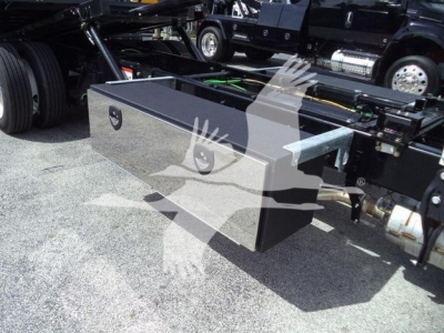 Data image of a truck rollback showing a metal toolbox mounted on the undercarriage with a latch handle. No visible model text legible.