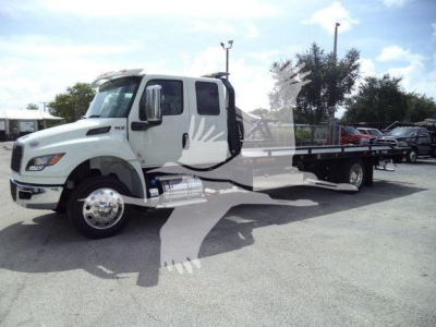 White International MV rollback tow truck from a side view showing flatbed and cab with chrome mirrors and dual rear wheels.