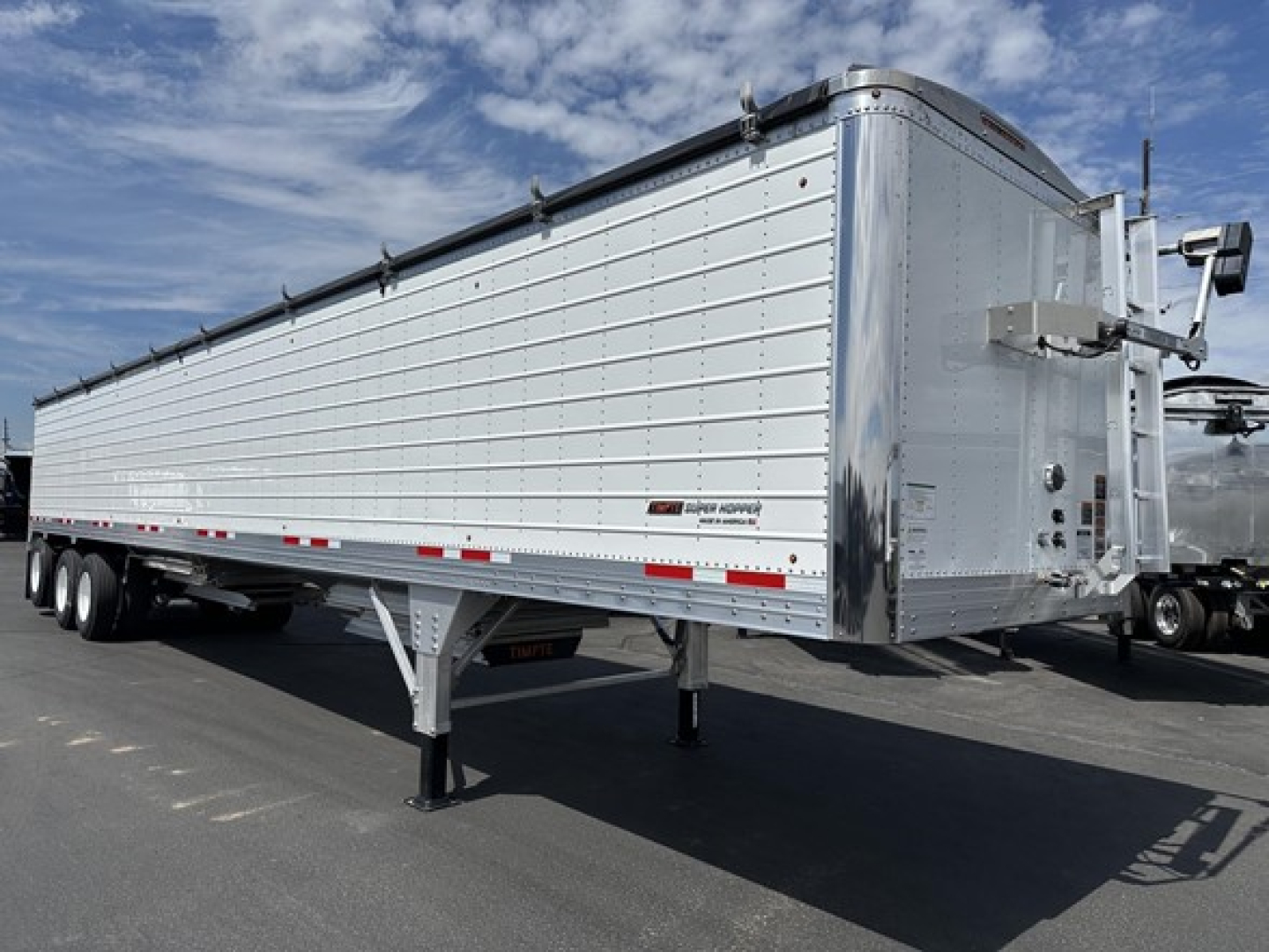 Timpte Super Hopper Tri Axle trailer in side and front view showing aluminum corrugated sides, dual rear axles, and front landing gear.