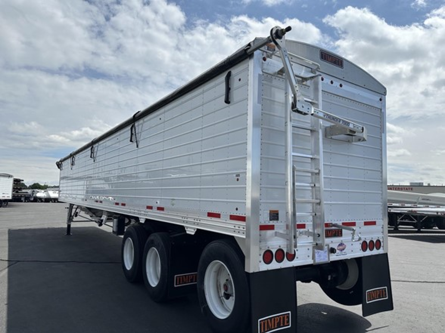 Timpte Super Hopper Tri Axle trailer rear and side view showing aluminum cargo box, wheels, ladder, and rear doors.