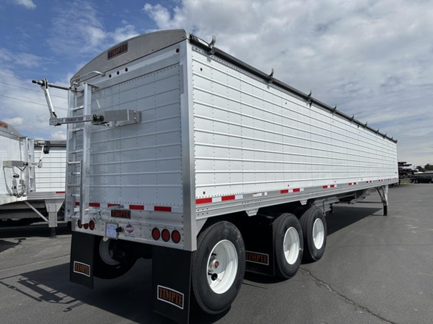 Timpte Super Hopper Tri Axle trailer showing triple axle rear, side paneling, and rear doors with taillights. Visible markings include Timpte branding on mudflaps and license plate area.