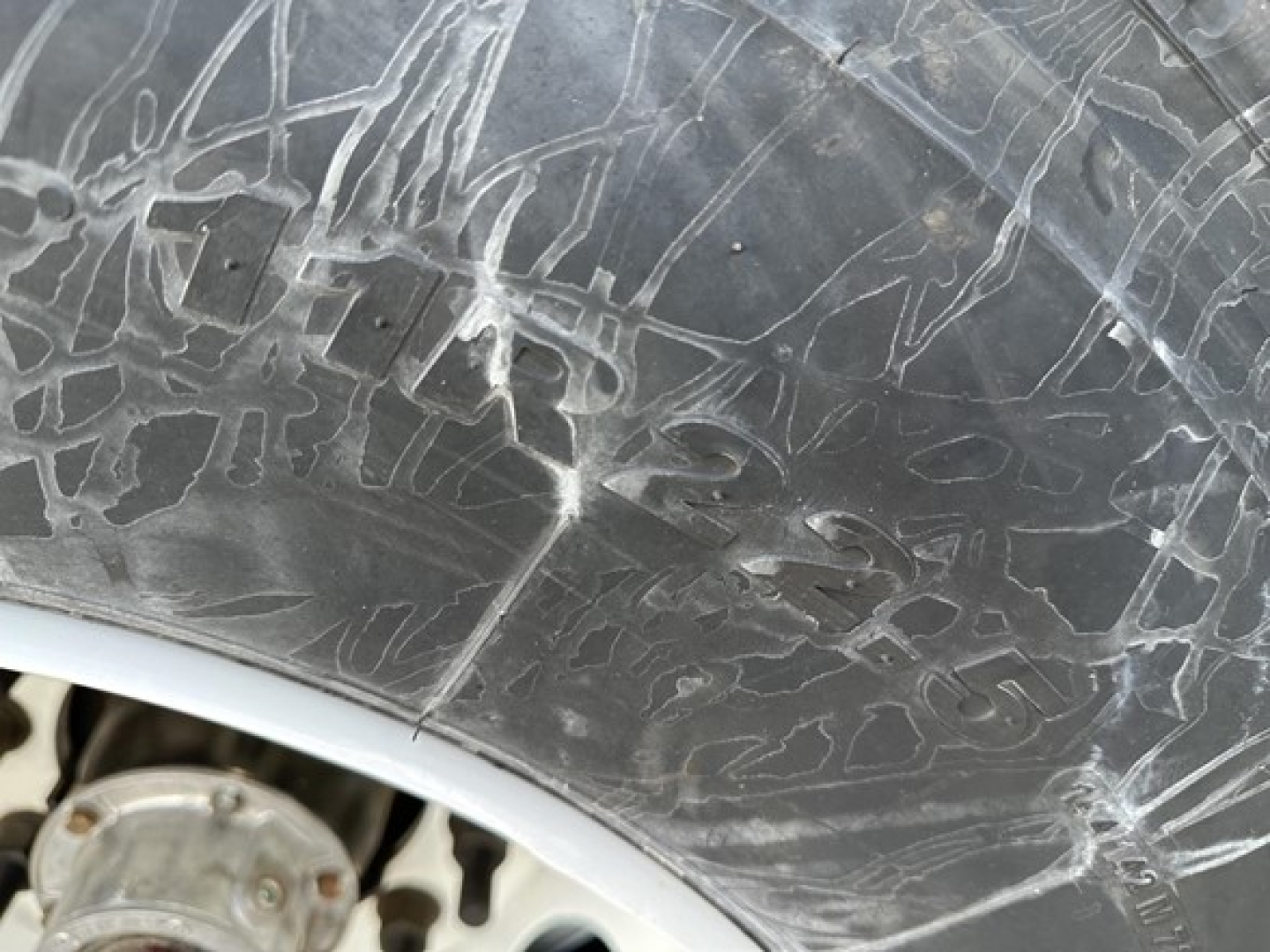 Tire sidewall image showing surface scratches and cracks with tire tread visible, no readable branding or numbers.