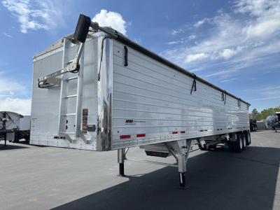 Timpte Super Hopper trailer in silver, side view, with rear access ladder and top hatch open, parked on lot.