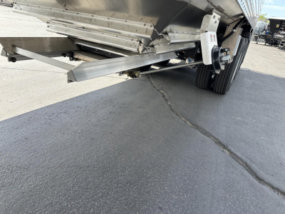 Trailer undercarriage showing landing legs and suspension; metal frame and hydraulic components visible.