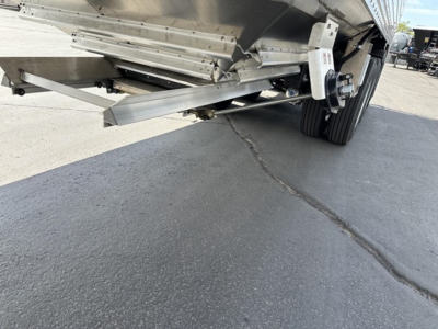 Trailer undercarriage showing aluminum support beams and suspension with wheels; close-up of underside near hitch area.