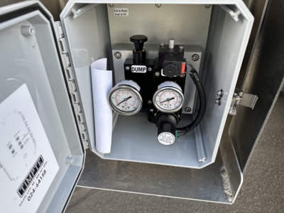 Timpte hopper trailer control box inside open compartment showing pump, two pressure gauges, manual lever, and labeled components.