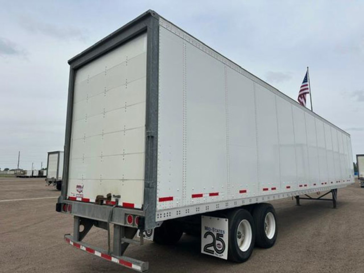 Trailer side and rear view of a 2016 Wabash van trailer with white walls, tandem axles, and red reflective tape.