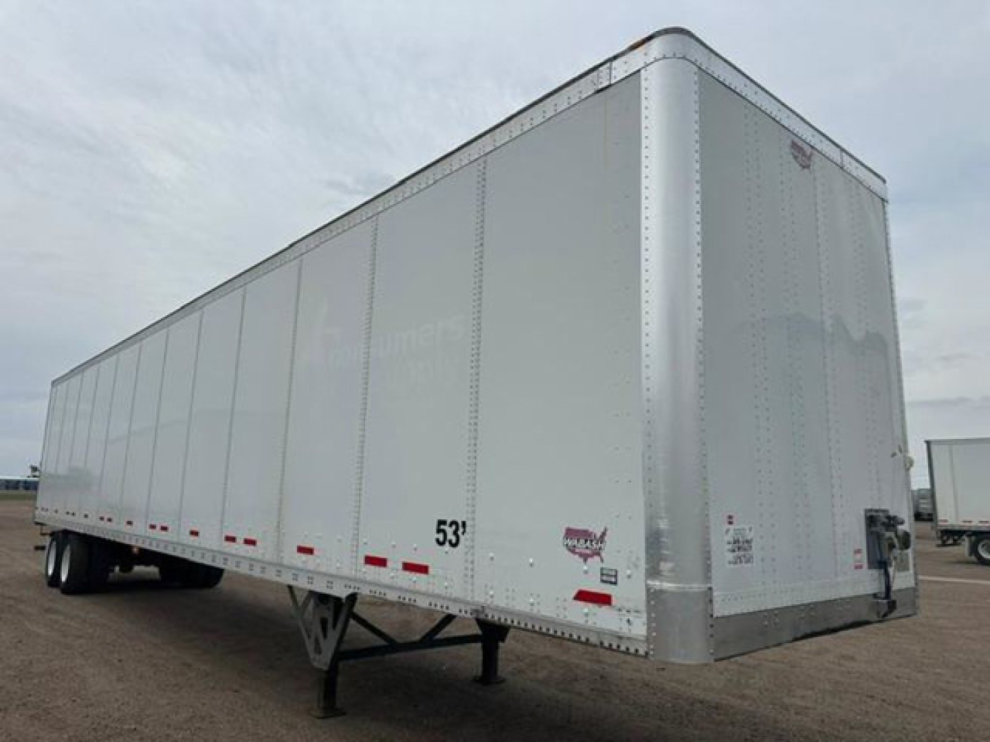 A 53' white Wabash trailer with riveted aluminum sides, viewed from the front-right, showing entry and rear supports; small decals near front corner.