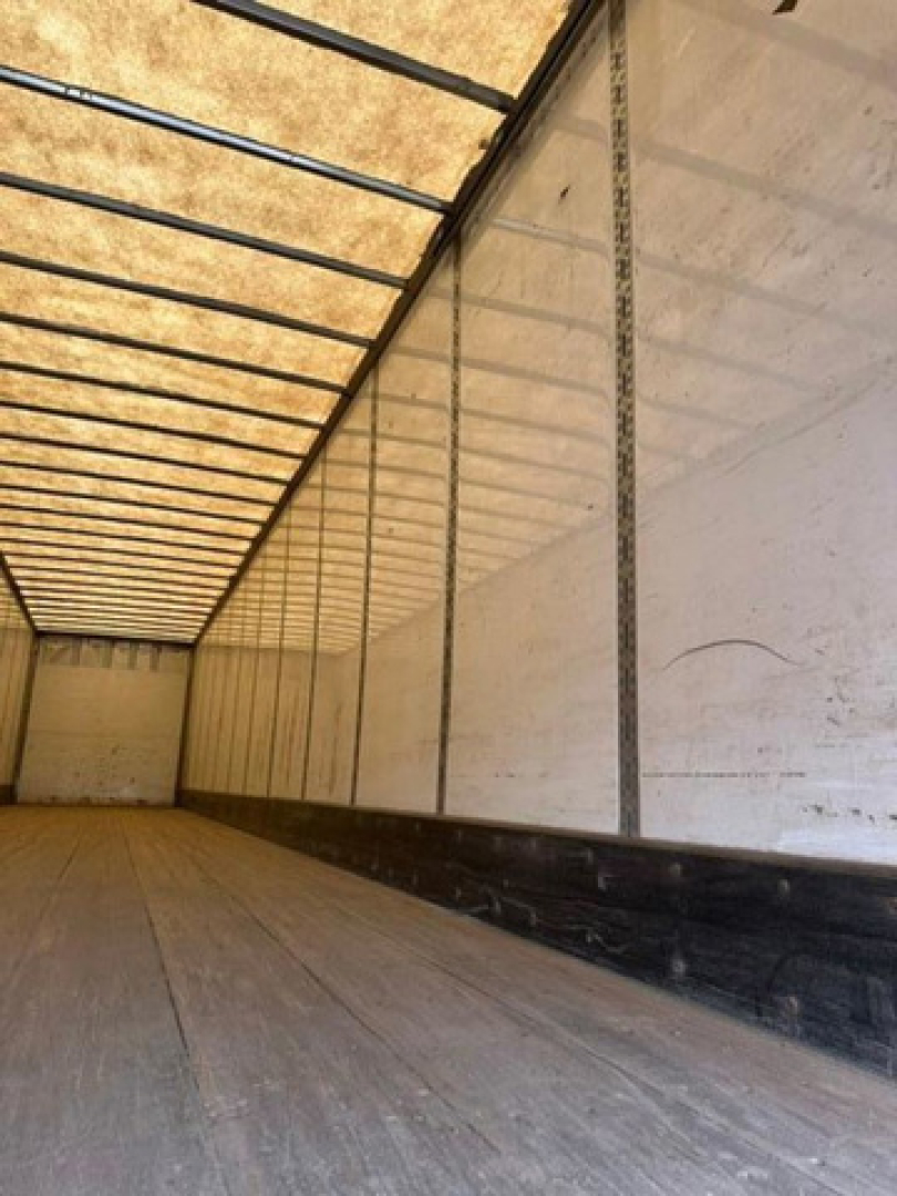 Trailer interior showing long empty cargo area with wooden floor and sidewall ribs, overhead ribs and roof panels visible.
